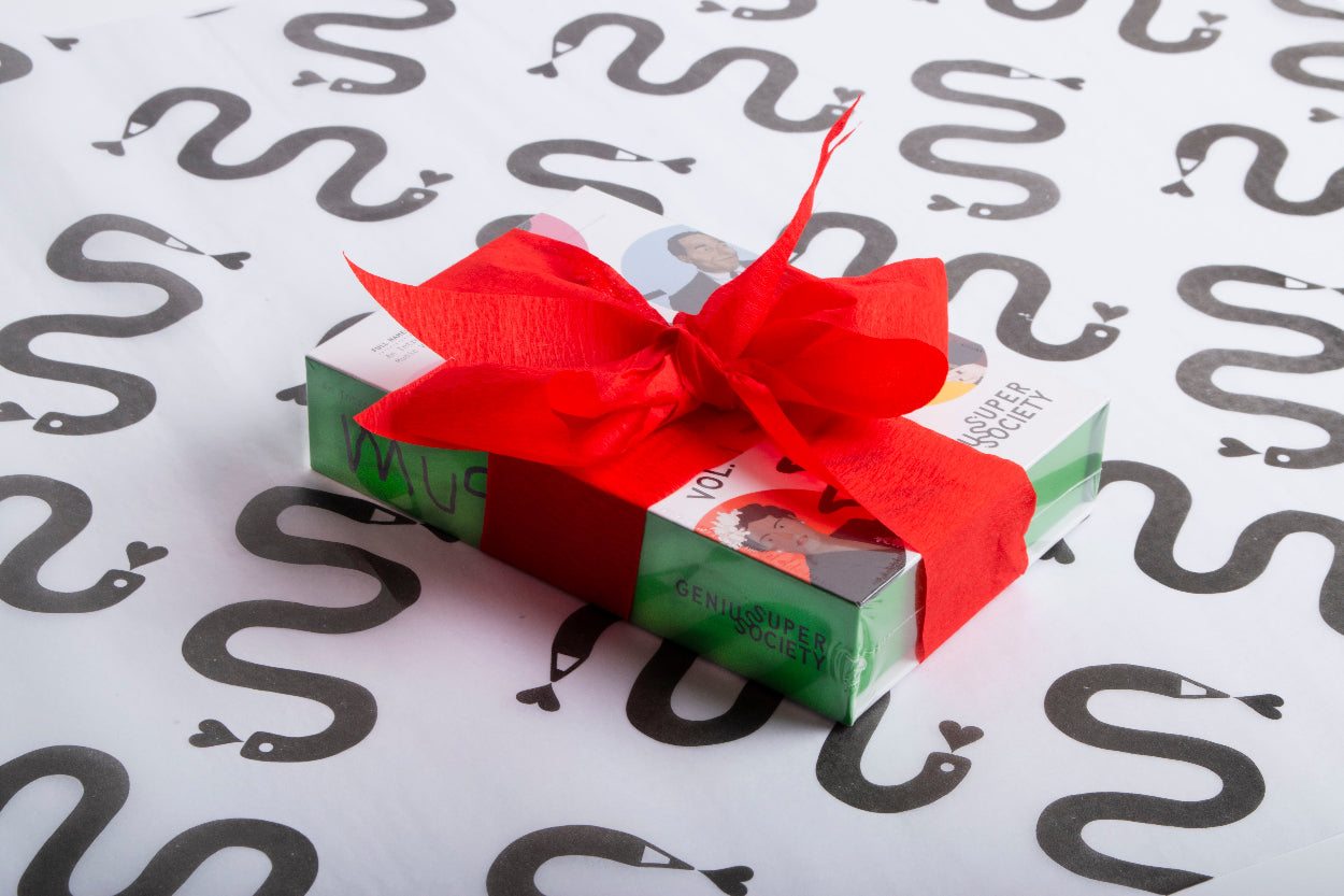 A Music Vol. 1 box of deck of music history cards with a festive red bow on a white background with black snake patterns